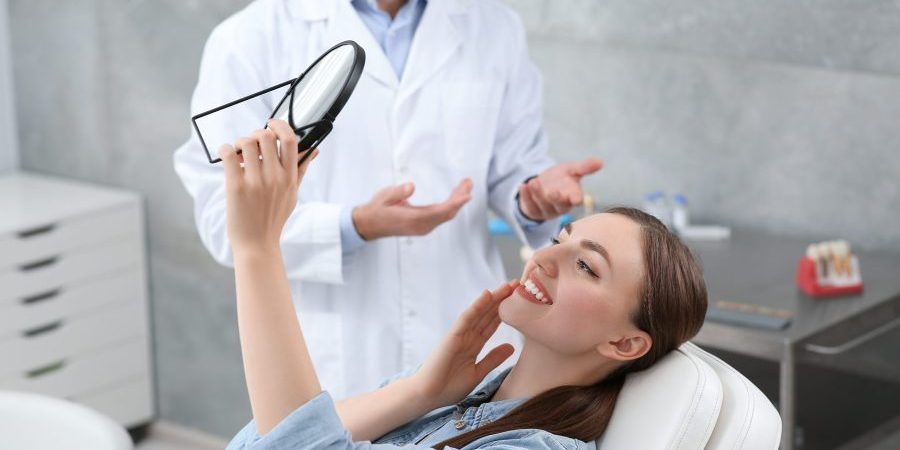 Young,Woman,Looking,At,Her,New,Dental,Implants,In,Mirror preventative dentist auburn